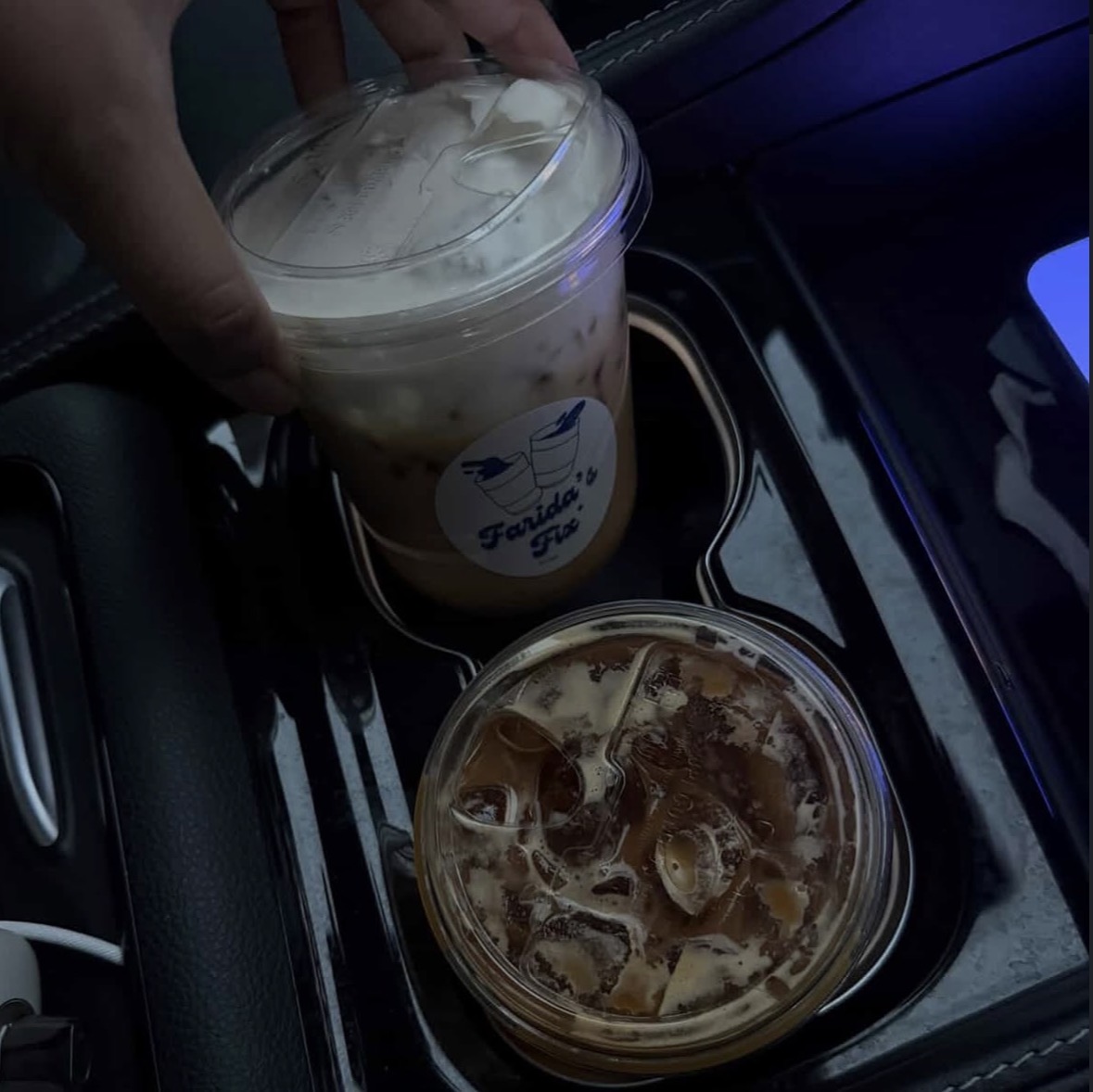 Two Farida's Fix branded iced drinks in a car cup holder
