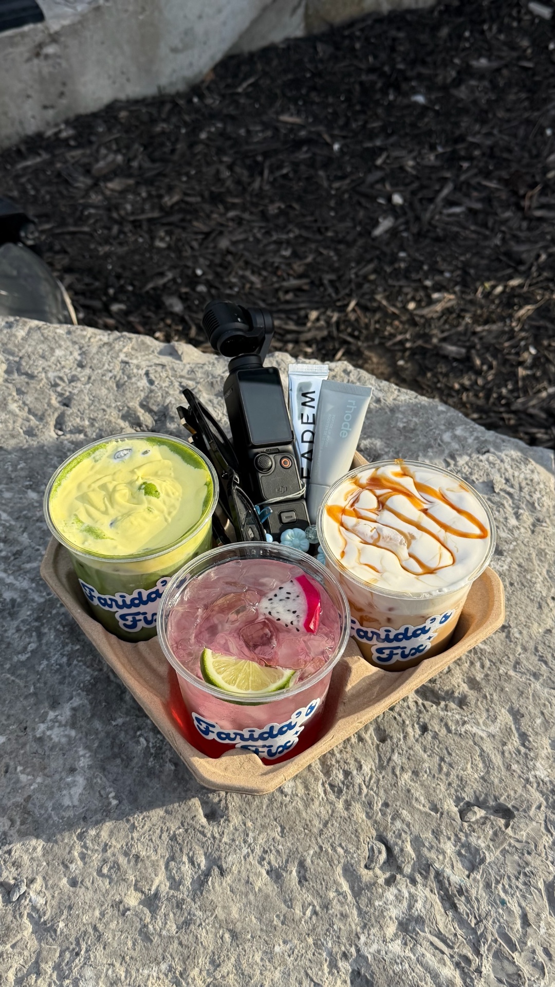 Trio of Farida's Fix branded iced drinks on a stone ledge